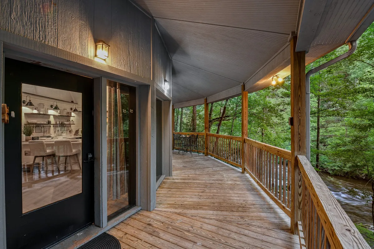 A welcoming wooden deck at the cottage entrance, framed by lush greenery and fitted with comfortable seating. The scene suggests an inviting transition between indoor comfort and outdoor adventure, perfect for relaxing after a stroll with your pet.
