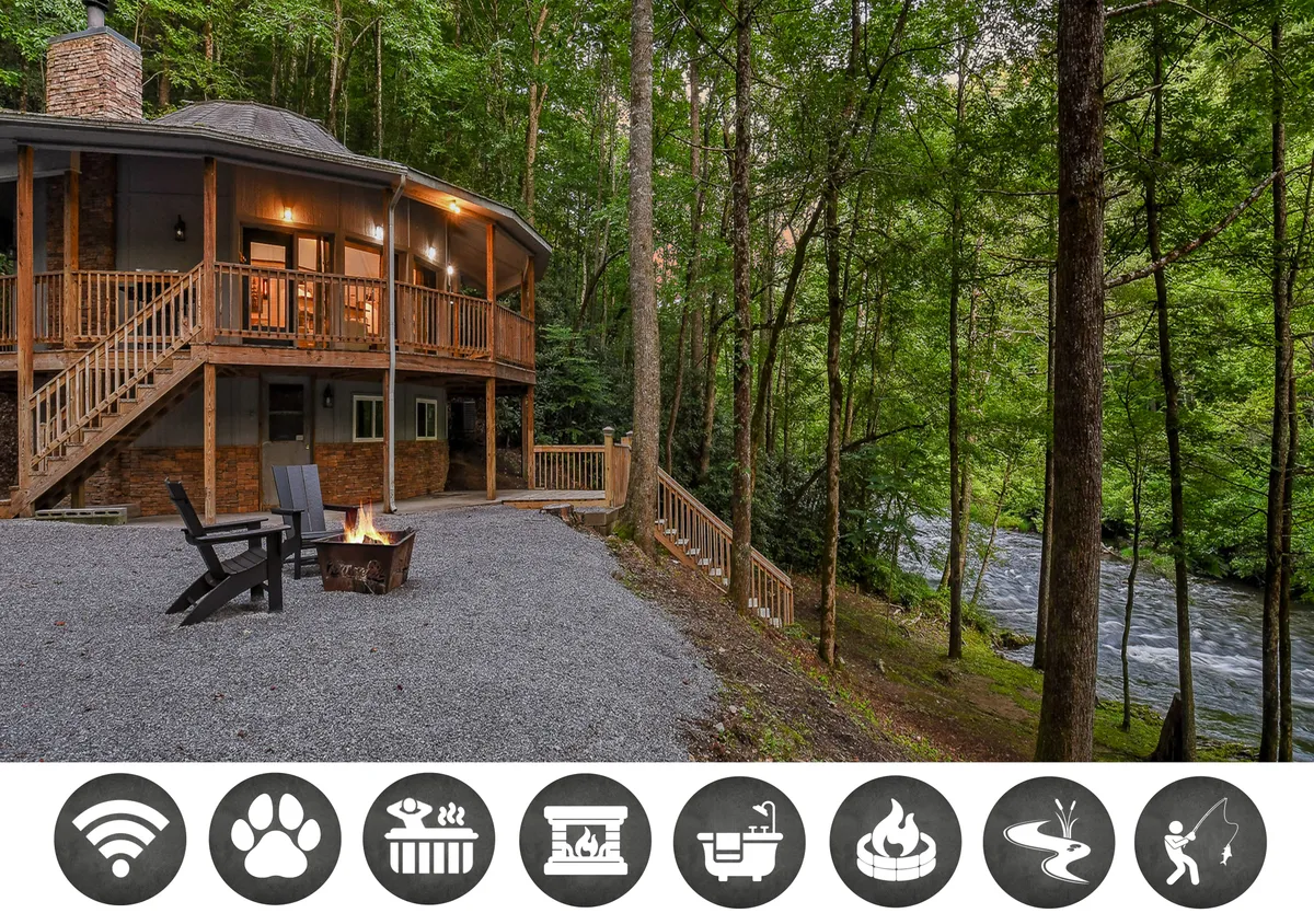 The image showcases the exterior of a cozy single-family cottage, featuring a wooden deck overlooking a peaceful river, a glowing fire pit surrounded by chairs, lush trees, and the warm colors of sunset filtering through the woods. The scene radiates tranquility and connection with nature, inviting relaxation and outdoor enjoyment.